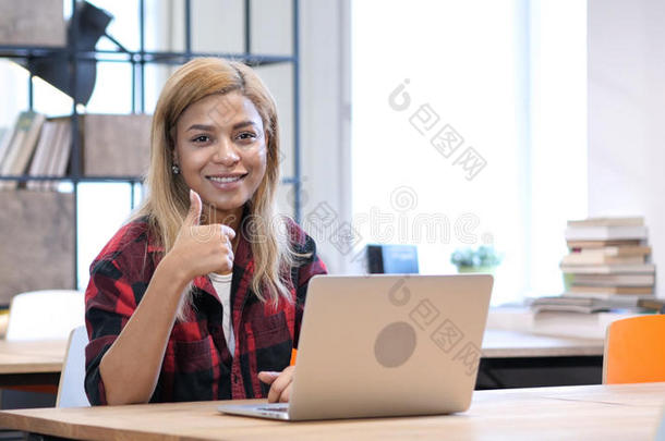 非洲式发型-美国人女人工作的向便携式<strong>电脑</strong>,拇指在上<strong>面对</strong>于照相机