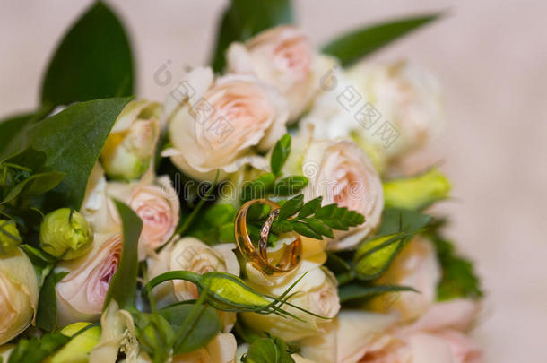 金色的婚礼戒指向婚礼花束关于粉红色的玫瑰