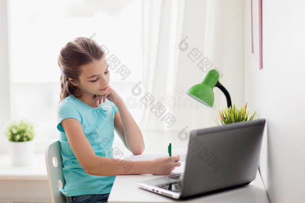 女孩和便携式电脑文字向笔记簿在家