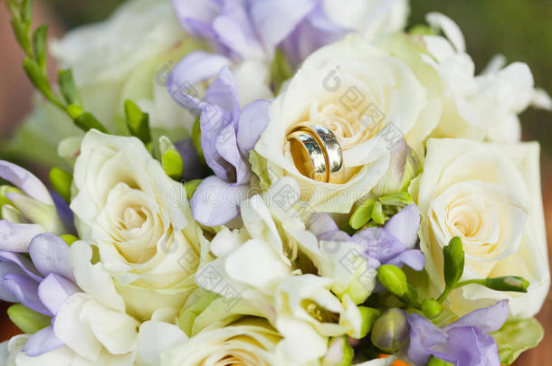 金色的婚礼戒指向婚礼花束关于白色的和紫罗兰流