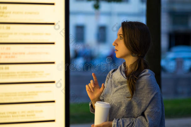 美丽的女人有样子的和兴趣向空白的广告牌决定