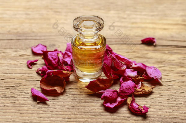瓶子和金色的基本的油和玫瑰花瓣向木材