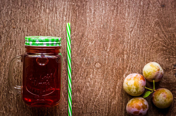 玻璃和新鲜的李子果汁向酿酒的木制的背景