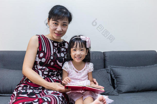 亚洲人中国人母亲和女儿阅读指已提到的人书向沙发