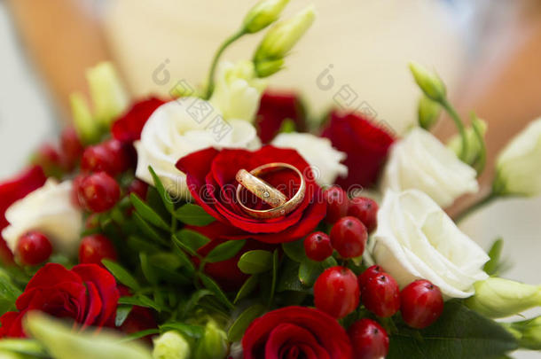 金色的婚礼戒指经过红色的浆果和白色的和红色的玫瑰英语字母表的第15个字母