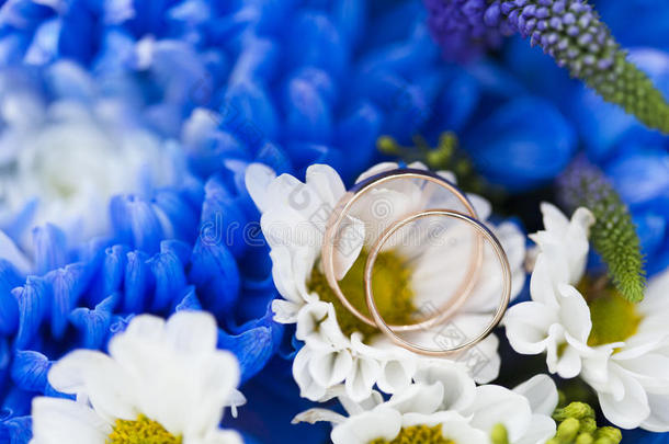 金色的婚礼戒指向婚礼花束英语字母表的第6个字母蓝色菊花和