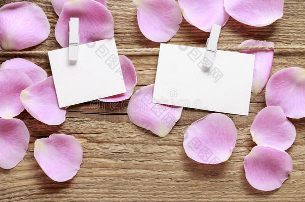 空白的纸卡片和粉红色的玫瑰花瓣向木制的背景