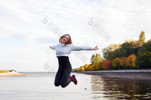 美丽的女孩用于跳跃的向指已提到的人公园路在近处湖.幸福和