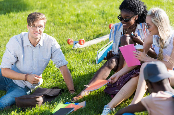 年幼的供多种族用的学生讲话和学习同时采用公园