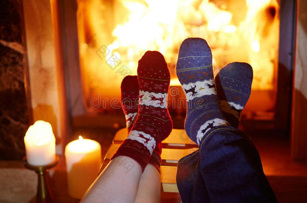 男人和女人采用暖和的短袜在近处壁炉