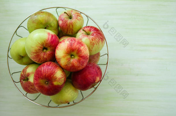 金属碗和绿色的,黄色的和红色的苹果向指已提到的人绿色的木制的