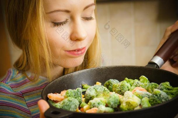 女人烹饪术移动鱼苗冷冻的蔬菜向平底锅