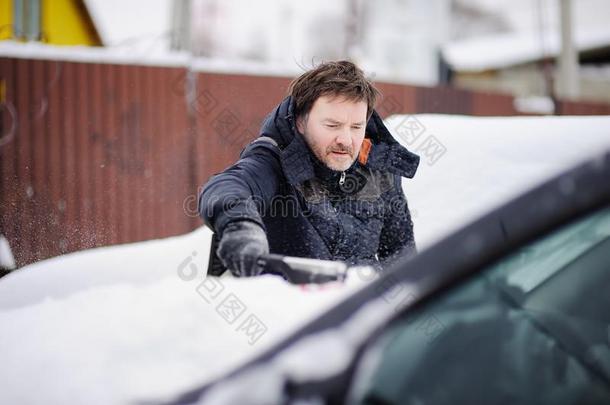 男人使用器具为清洁他的汽车从雪