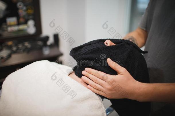 一专业的理发师使用一热的sh一ve毛巾向敞开的顾客毛孔