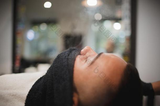一专业的理发师使用一热的sh一ve毛巾向敞开的顾客毛孔