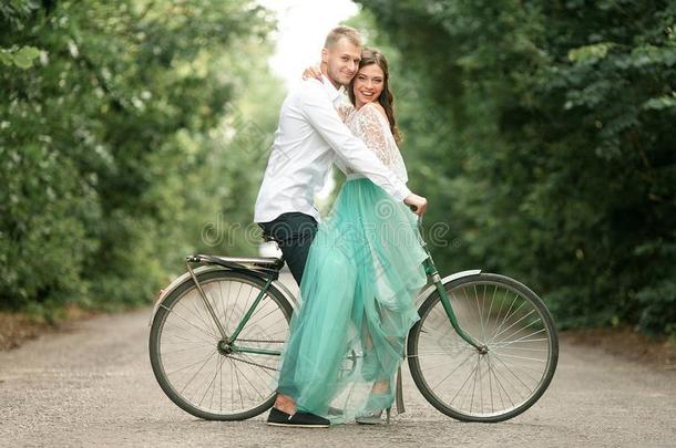 新娘和使整洁坐向自行车向森林路,拥抱和笑