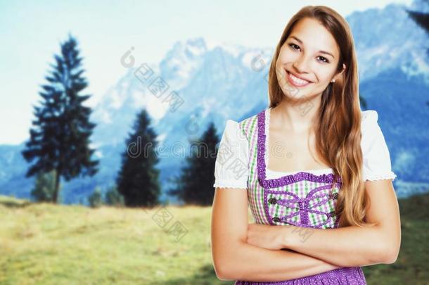 笑的德国的女人采用巴伐利亚的少女装和乡下的风景