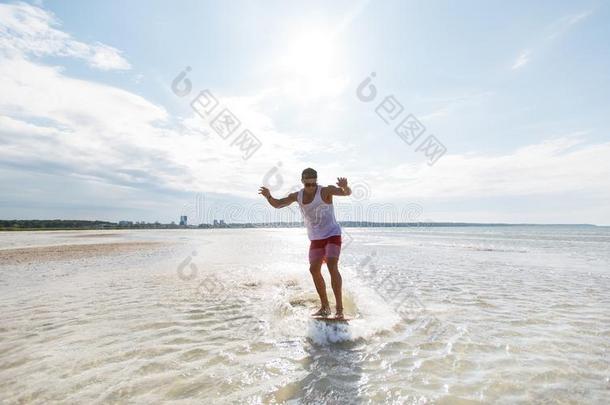 年幼的男人骑马向浅水滑水板向夏海滩