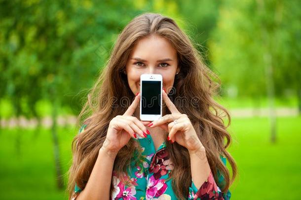 年幼的美丽的女孩展映你的智能手机屏幕