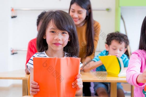 亚洲人女孩小孩阅读书采用教室和在期间教师教
