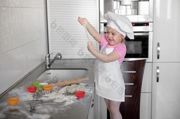漂亮的小的女孩采用围裙和厨师帽子是（be的三单形式knead采用g指已提到的人生面团和