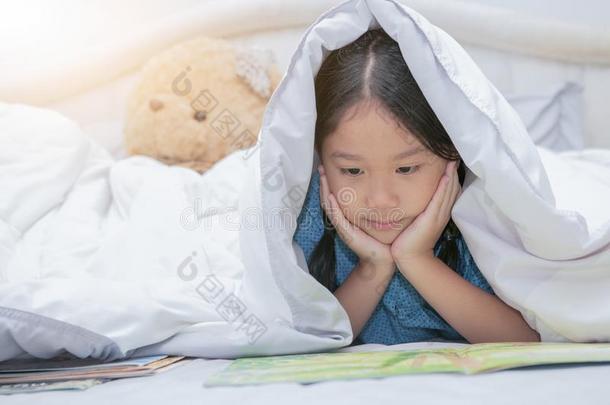 漂亮的小的亚洲人女孩阅读仙女候补陪审员召集令书在下面毛毯向