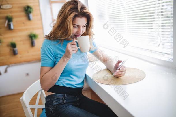 美丽的亚麻色的女人喝饮料咖啡豆和阅读新闻