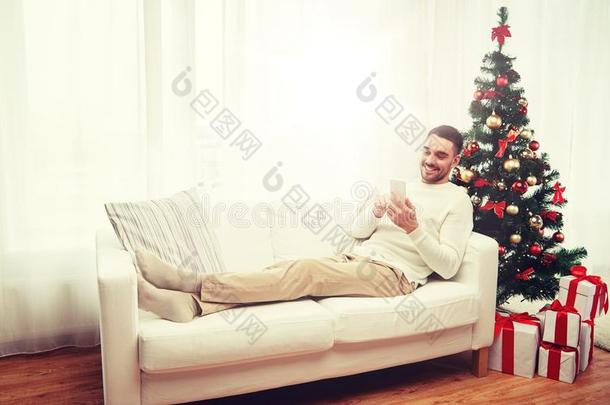 微笑的男人和智能手机在家为圣诞节