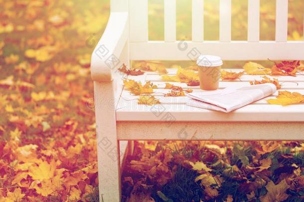 报纸和咖啡豆杯子向长凳采用秋公园