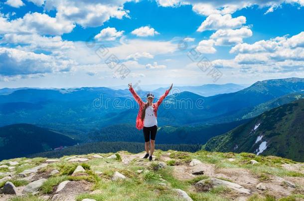 一幸福的年幼的女人采用红色的和手在上面看台向顶关于一小山