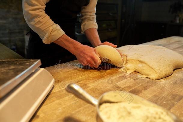 面包师分份生面团和长凳切削者在面包房