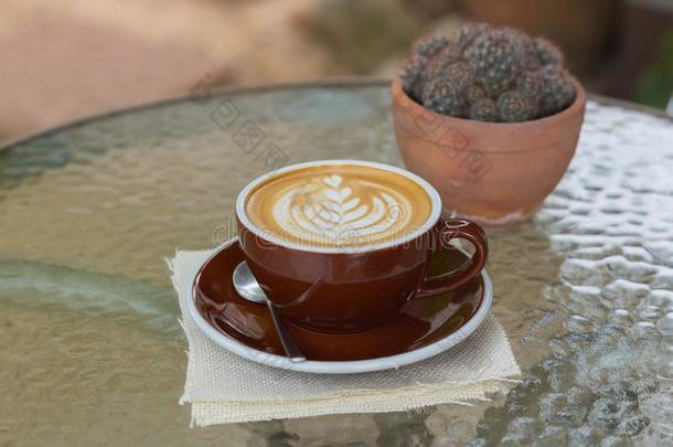 热的咖啡豆拿铁咖啡和美丽的起泡沫艺术向玻璃表.户外的