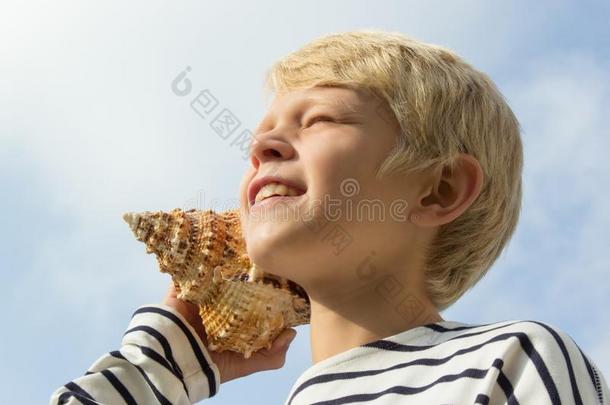 小孩倾听向海中软体动物的壳