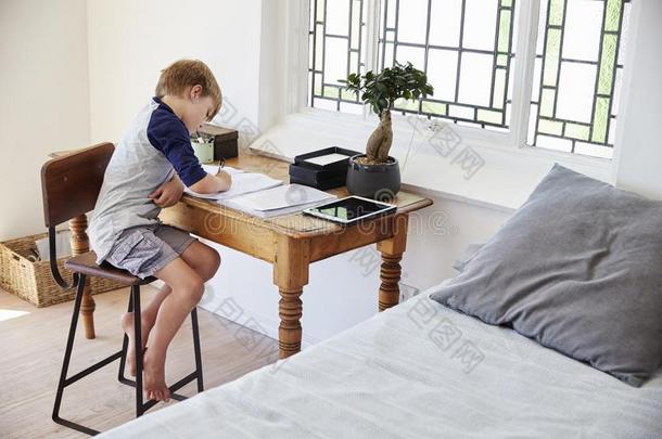 男孩坐在书桌采用卧室和数字的碑做家庭作业