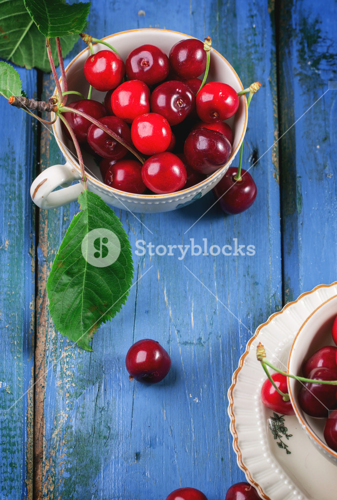 陈年茶杯里有一些新鲜的樱桃ins简约风背景图片