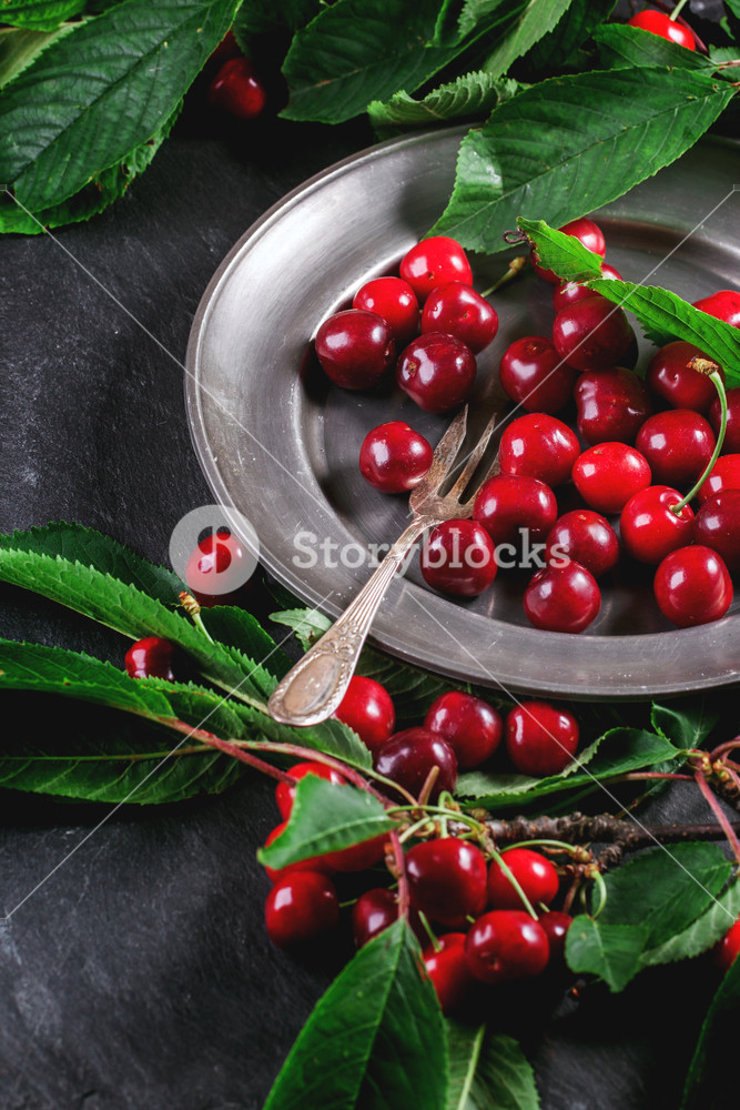 一大盘美味的樱桃和餐具摆在桌面上的背景图片